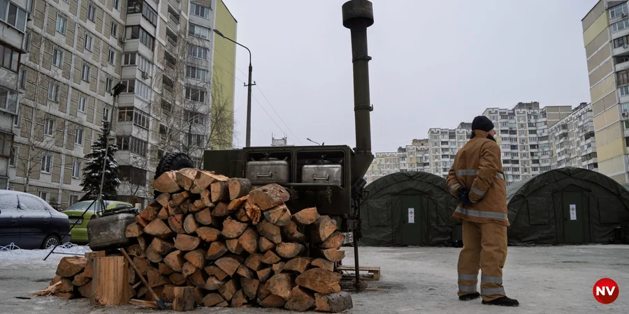 Працівник ДСНС стоїть на фоні розгорнутого наметового містечка на столичній Троєщині. Фото: Сергій Окунєв