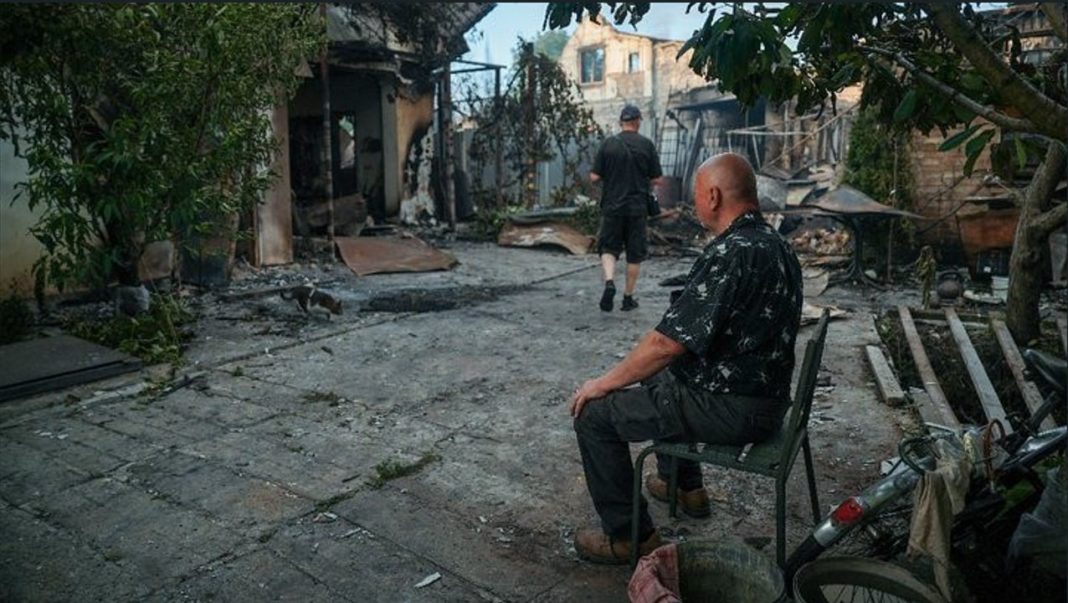 Житель Вишневого сидить навпроти згорілого будинку. Фото: Суспільне/Оксана Сенів